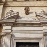 Il portale ligneo � inquadrato da pi� cornici rettangolari, affiancate da quattro paraste scanalate con capitelli ionici. Questi reggono un timpano ad arco spezzato su cui domina lo stemma lapideo delle Carmelitane, con tre stelle e una croce centrale 